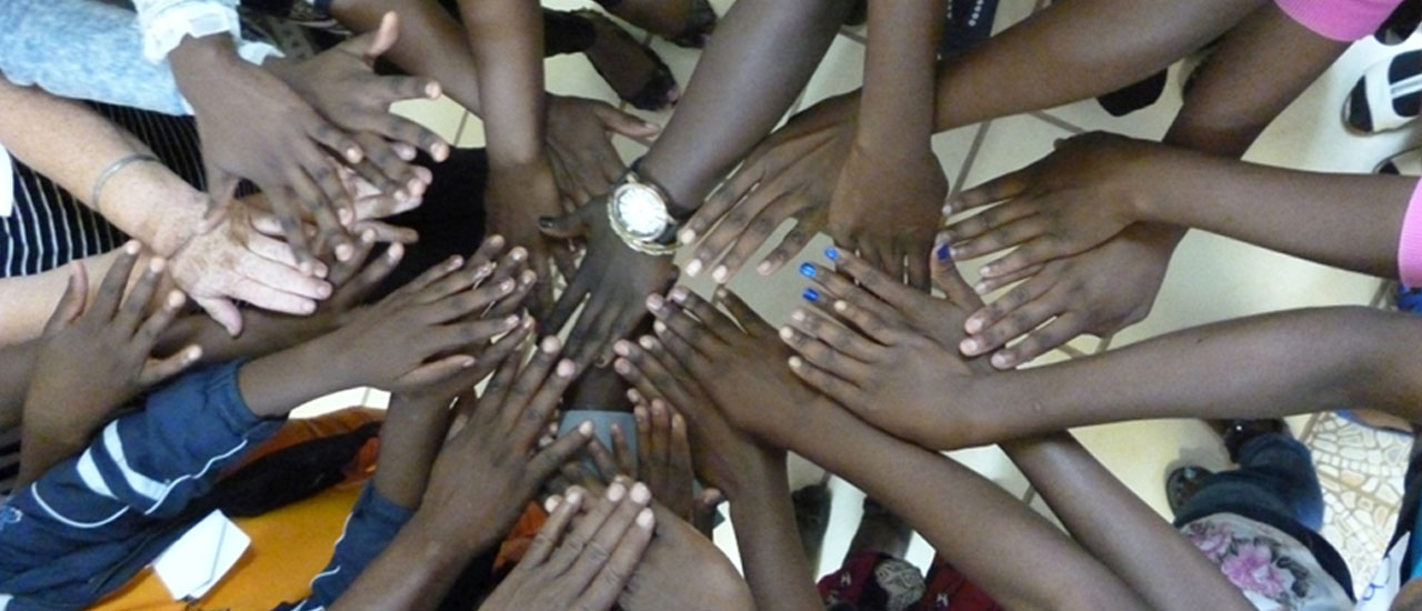 Hands touching other hands in a circle. Credit: Co-Production of a Support Group Curriculum for and with adolescent girls living with HIV, Zambart, ICRW &amp; LSHTM, MAC AIDS Foundation