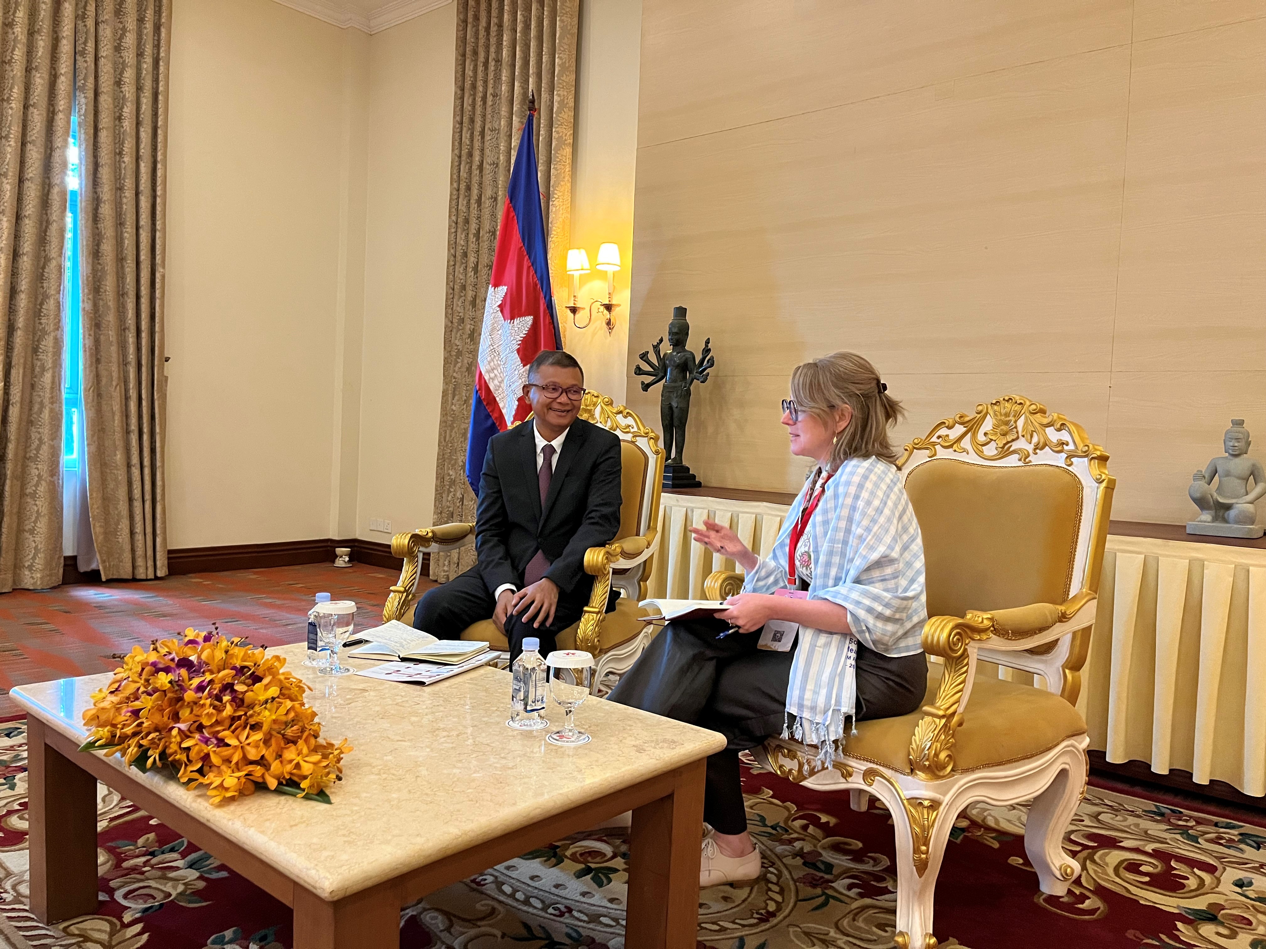 A woman and a man sit at a table in a formal reception room