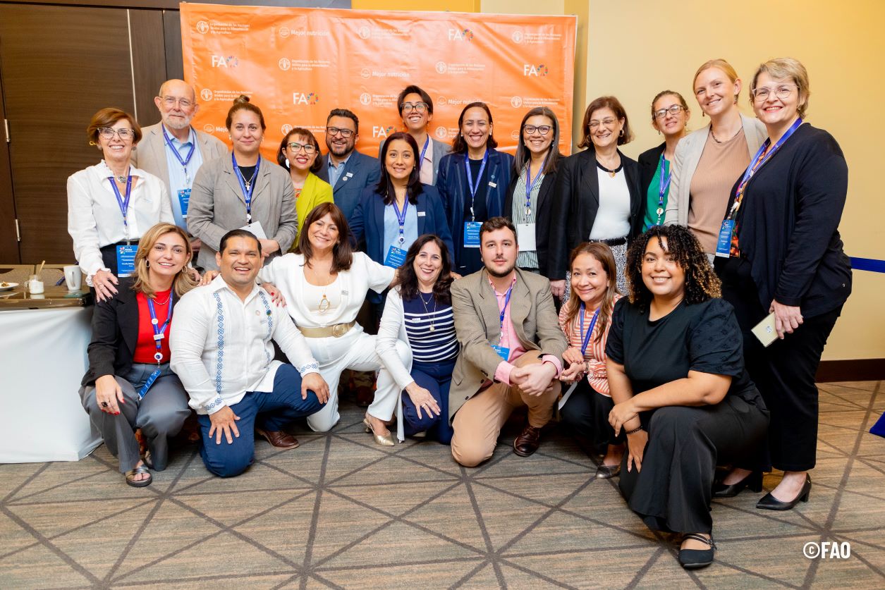 A group of men and women from Latin America, Europe and North America smile and pose at a conference