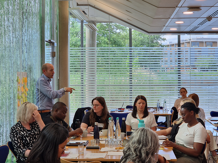 Ed Newman, UK-PHRST Director standing talking to sitting deployment training attendees in a room with glass walls