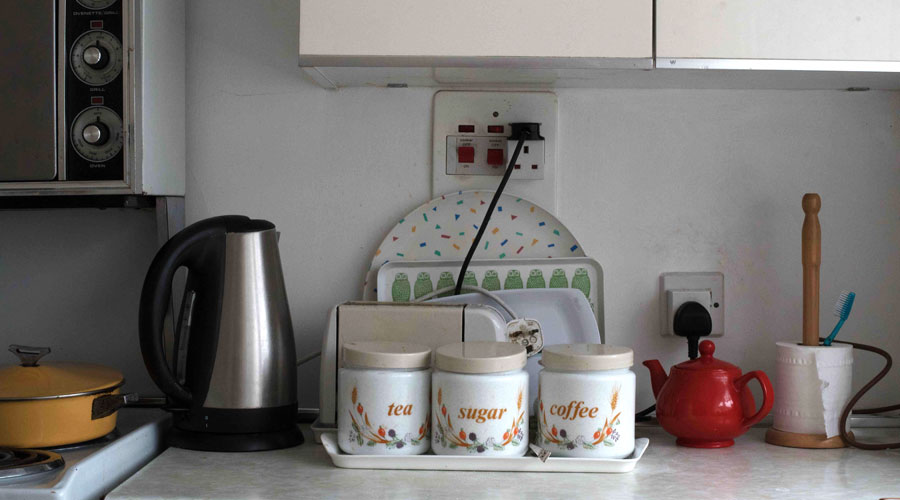 Kettle, and tea, coffee and sugar jars on a counter in home