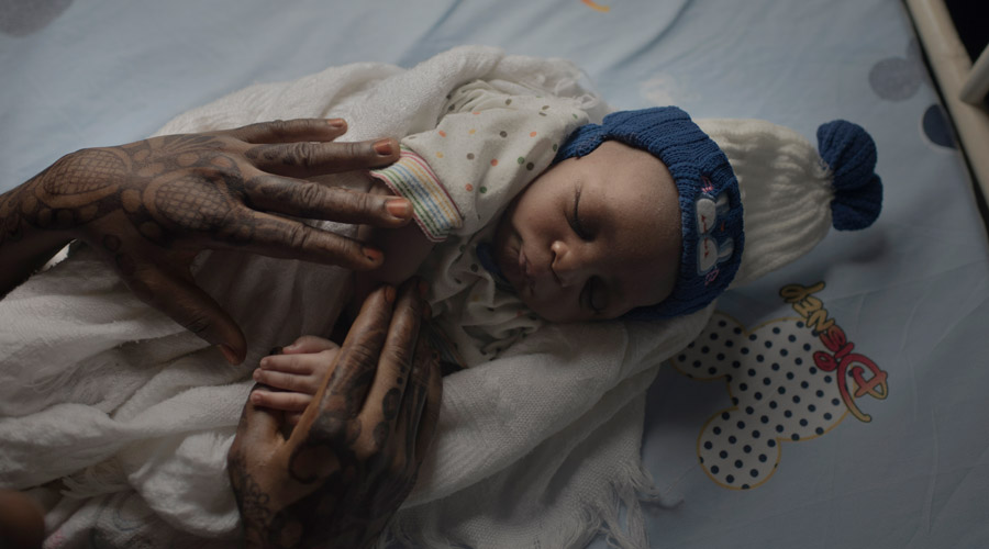 Hands of mother on sleeping newborn