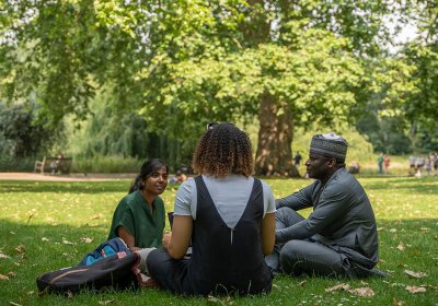 Three students sat in a park in London.