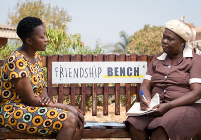 A Friendship Bench Grandmother sitting with her client on simple wooden park bench in Zimbabwe. 