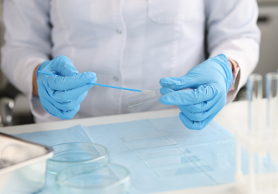 Doctor in gloves holds brush for smear and glass in lab. Credit: Canva/Alexander&#039;s images