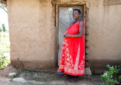 A pregnant women in a red dress standing in front of a door