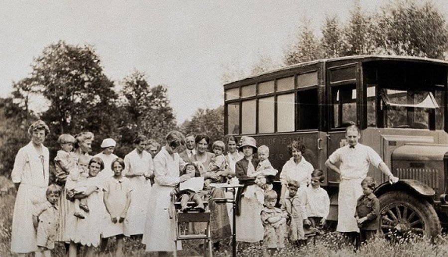 A mobile health unit, parked in a Pennsylvania field: women and their children are shown receiving treatment from the unit&#039;s health practitioners. Photograph, 1920/1930? Wellcome Collection