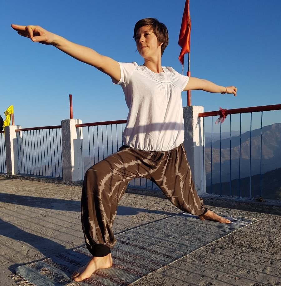 Female striking a yoga pose on a mat on the top of a mountain